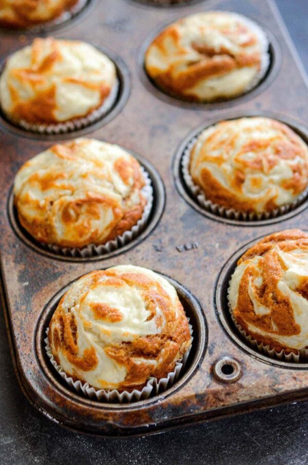 Pumpkin cream cheese muffins in a muffin baking pan. 
