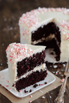 Slice of Chocolate Peppermint Dream Cake covered in crushed peppermint on a white plate with a fork
