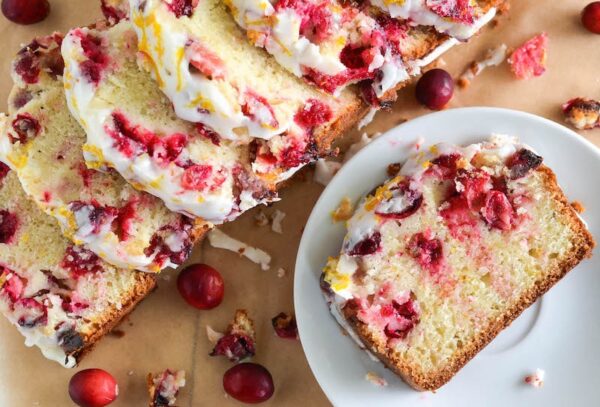 Cranberry Orange Bread sliced into pieces with one piece on a plate.