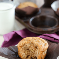Banana Brown Sugar Muffins with a bite taken out of one with a glass of milk in a clear glass