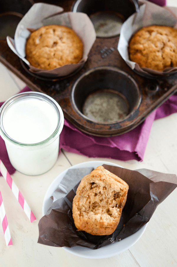 Banana Brown Sugar Muffins with a bite taken out of one with a glass of milk in a clear glass