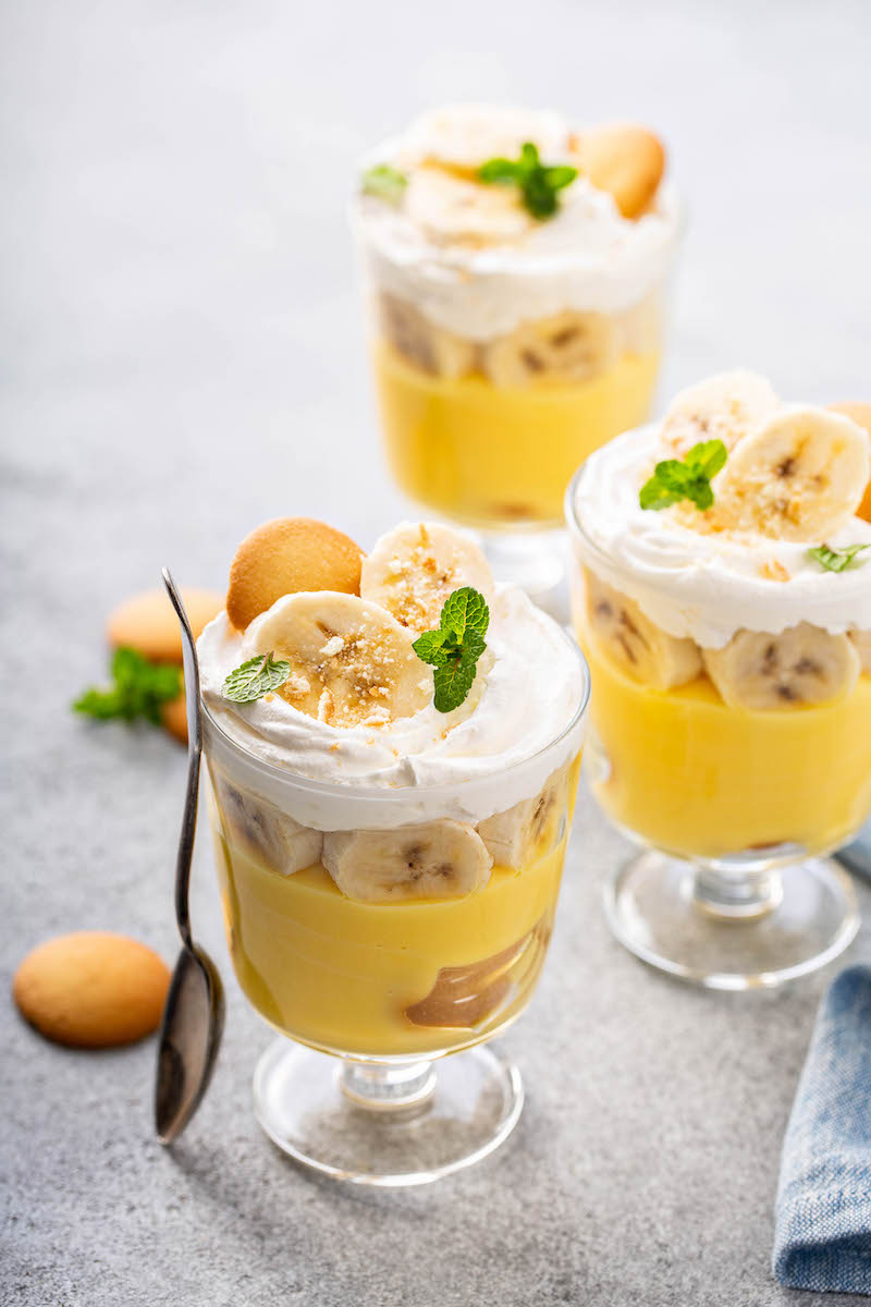 Three jars of banana pudding trifles decorate with vanilla wafers and banana slices.