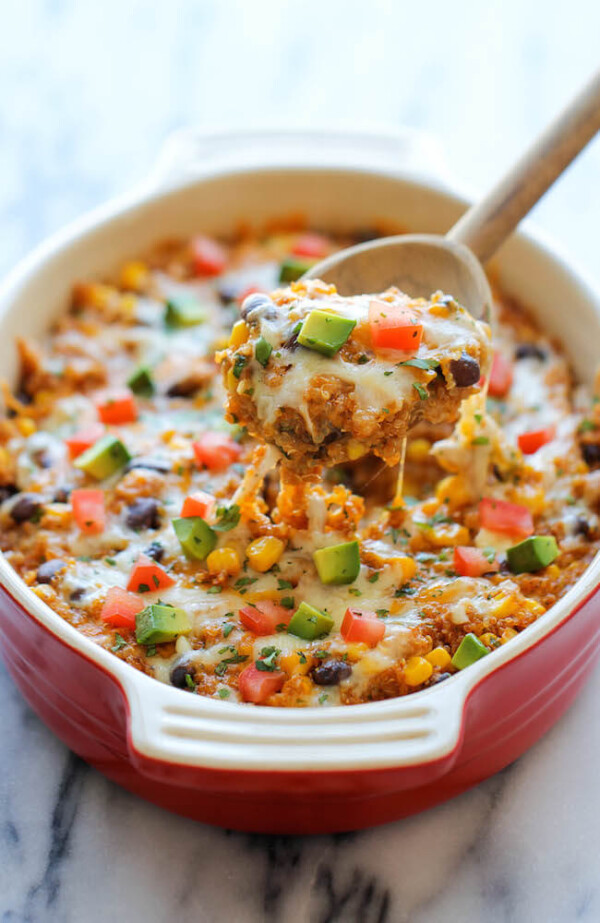 Scooping a Quinoa Enchilada Casserole with a Wooden Spoon
