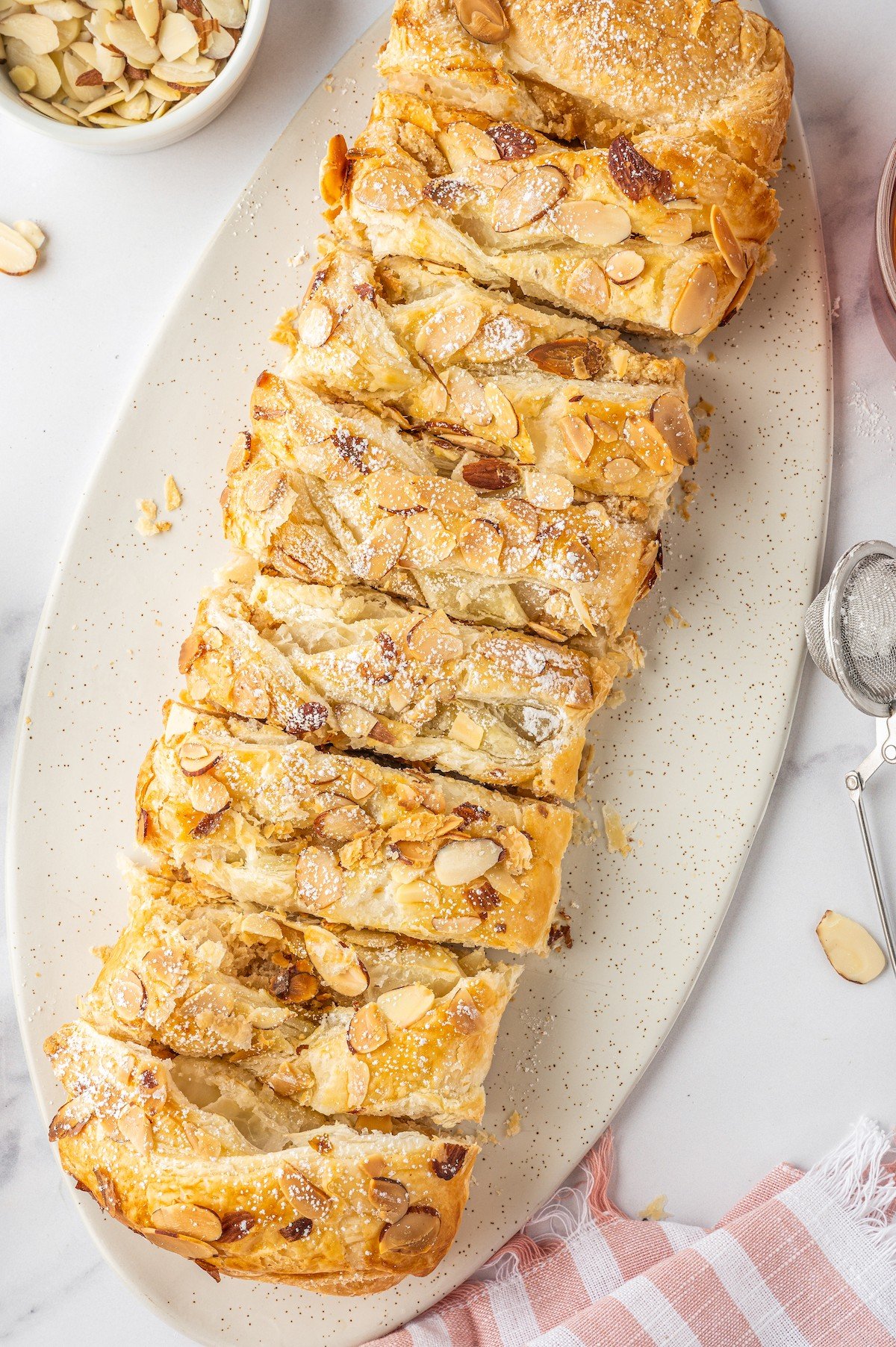 A braided pastry topped with sliced almonds.