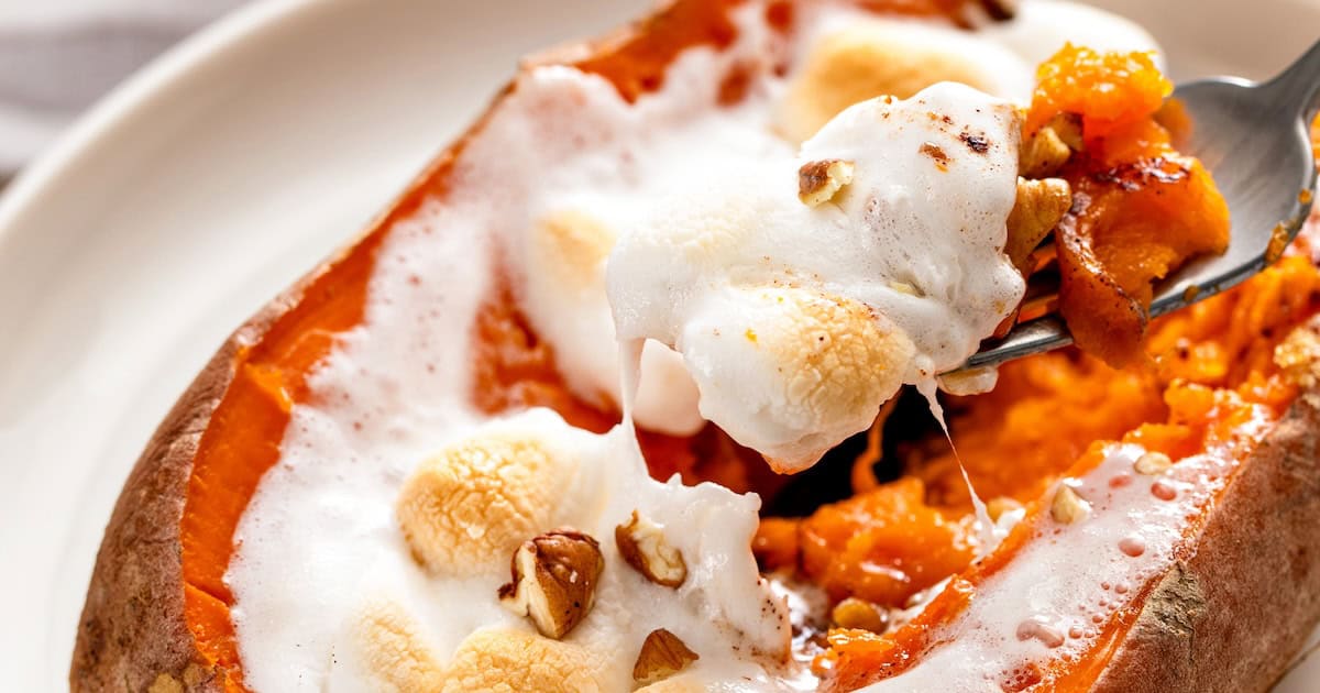 Marshmallows melted across the top of a baked sweet potato.