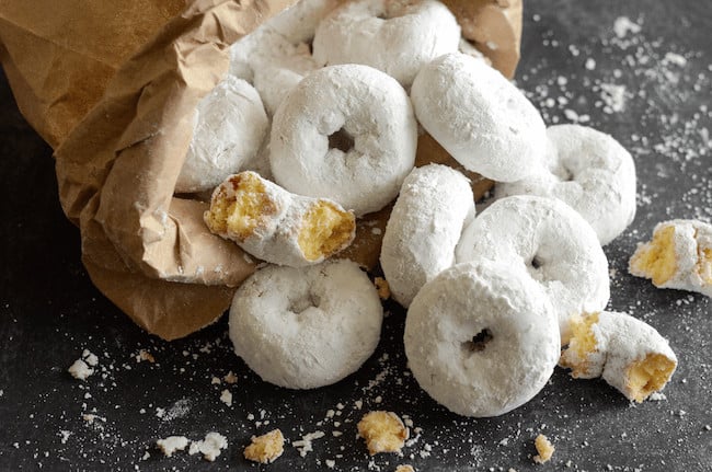 A Bag of Mini Powdered Donuts Spilling Out Onto a Black Countertop