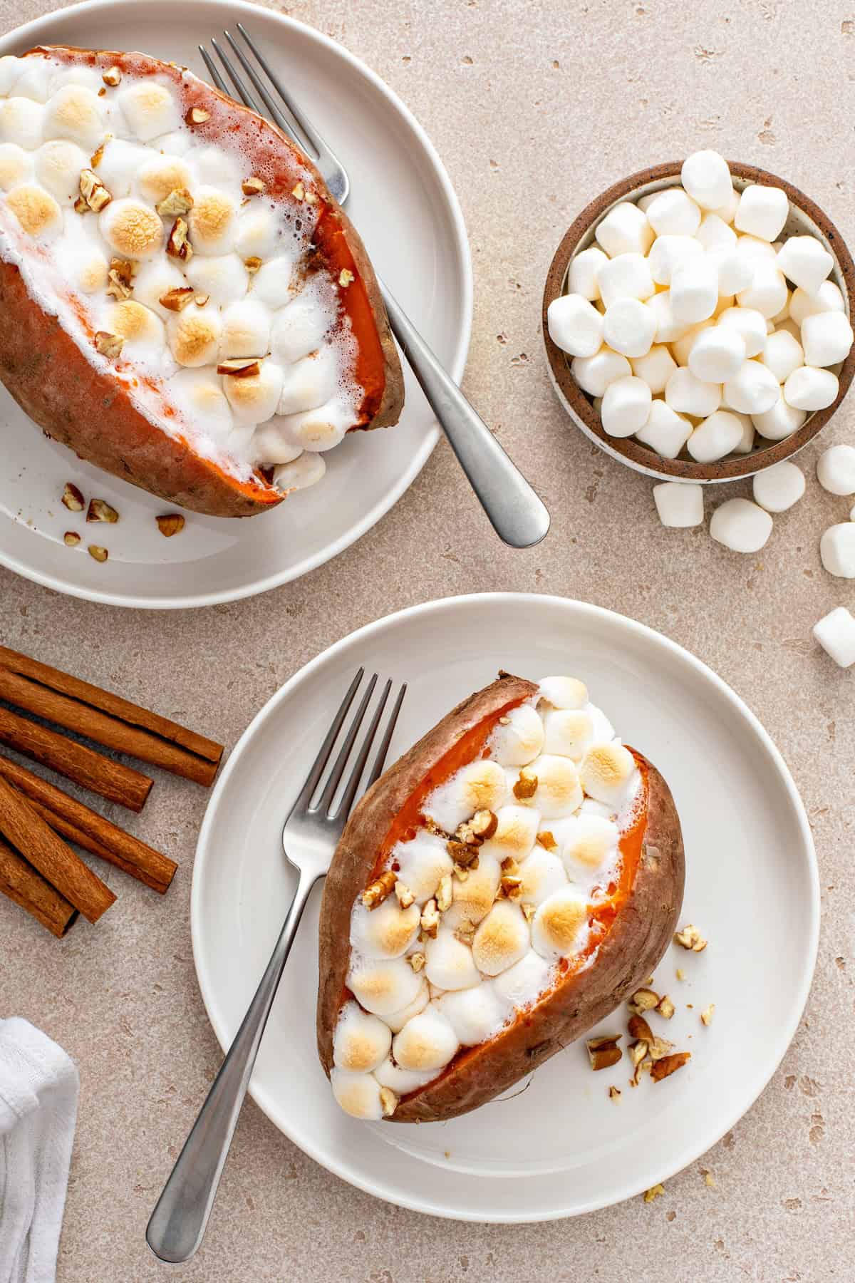 Marshmallow stuffed sweet potatoes on white plates.