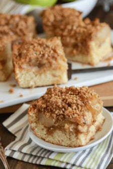 Close up of a slice of Cinnamon Apple Buckle on a white plate with remaining buckle in the background