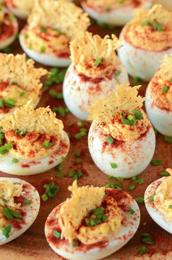Top view of Deviled Eggs on a wood board with cheese crisps and chives