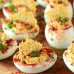 A bunch of Deviled Eggs with a cheese crisp and paprika sprinkled on top of each one