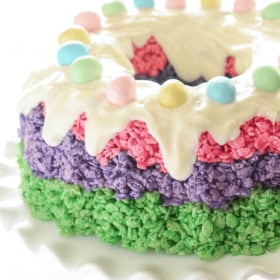 Easter Rice Krispie Cake topped with icing and robin's eggs on a white cake stand.