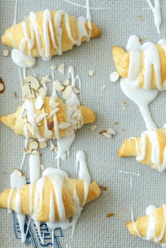 Almond Stuffed Crescent Rolls Lined up on a Baking Sheet with Icing Drizzled Over Them