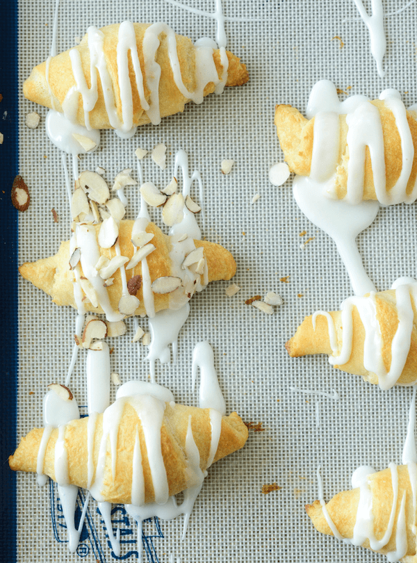Almond Stuffed Crescent Rolls Lined up on a Baking Sheet with Icing Drizzled Over Them