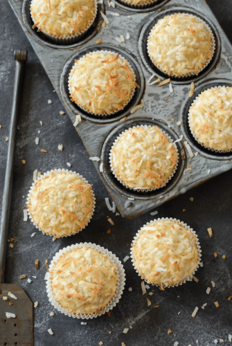 Coconut Banana Crunch Muffins in muffin tin and on a dark surface