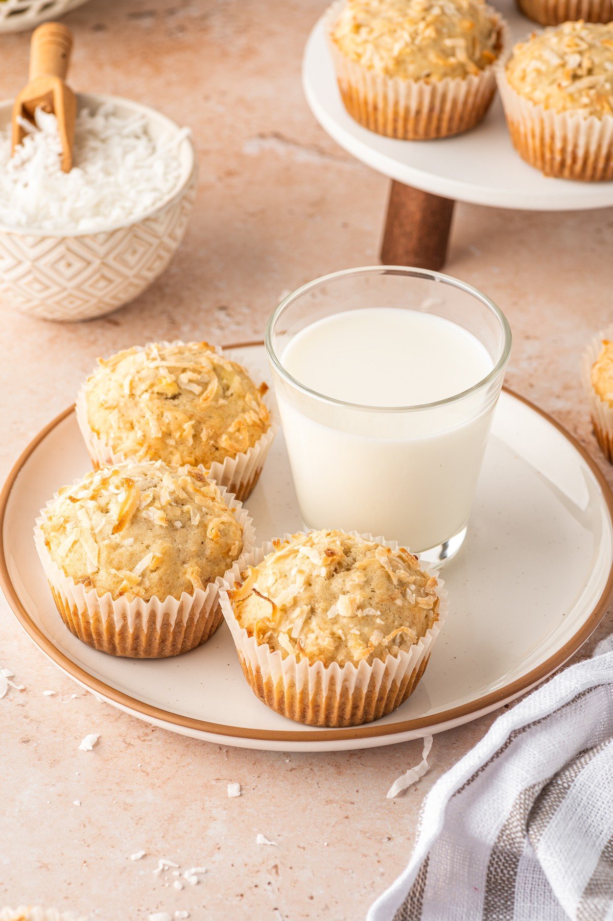 Three muffins with a glass of milk on the side. 