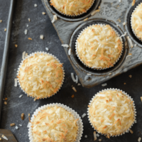 Coconut Banana Crunch Muffins in muffin tin and on a dark surface