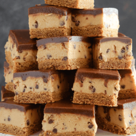 Peanut Butter Cookie Dough Bars stacked on a white cake stand
