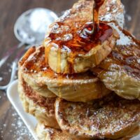 A Stack of Cuban Bread French Toast with Syrup Drizzled on Top