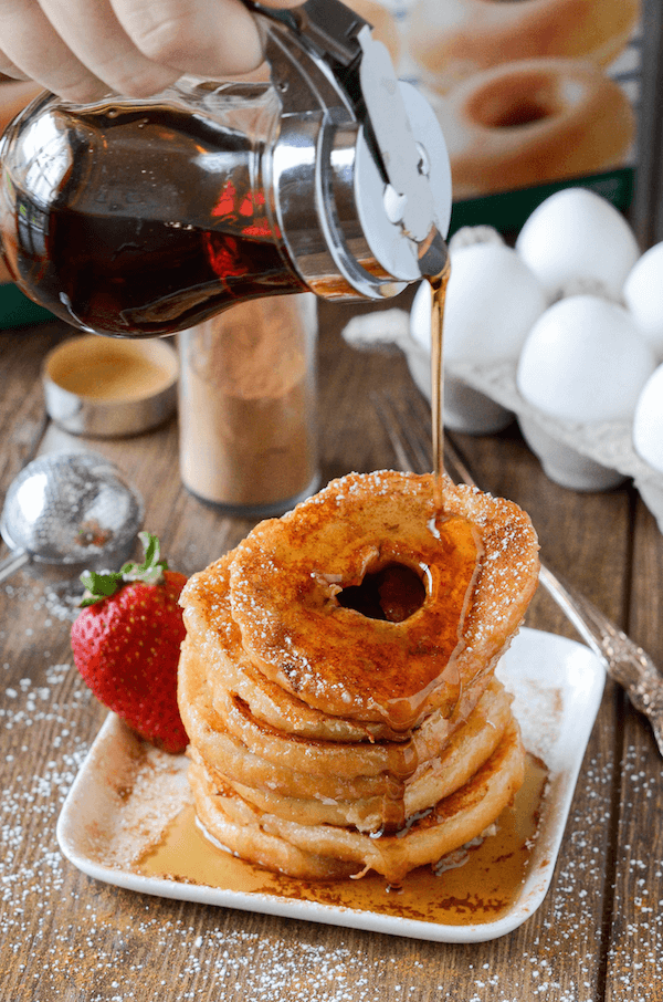 A stack of donut french toast with syrup being poured on top. 