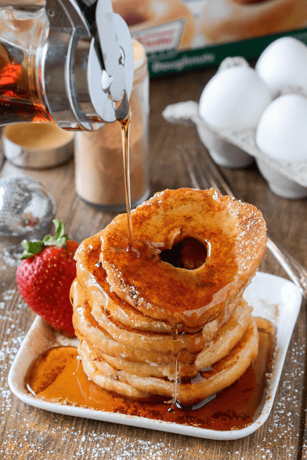 Donut French Toast on a plate with a strawberry and syrup being poured on top. 