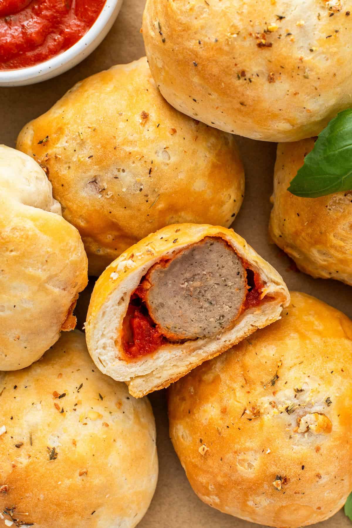 Stuffed with a saucy meatball and gooey melted cheese, these easy-to-make Meatball Bombs are topped with garlic butter for a flavorful bite! A single meatball bomb has been cut in half to reveal a fully cooked center.