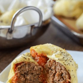 Meatball Bombs cut in half showing meatball with sauce on a white plate