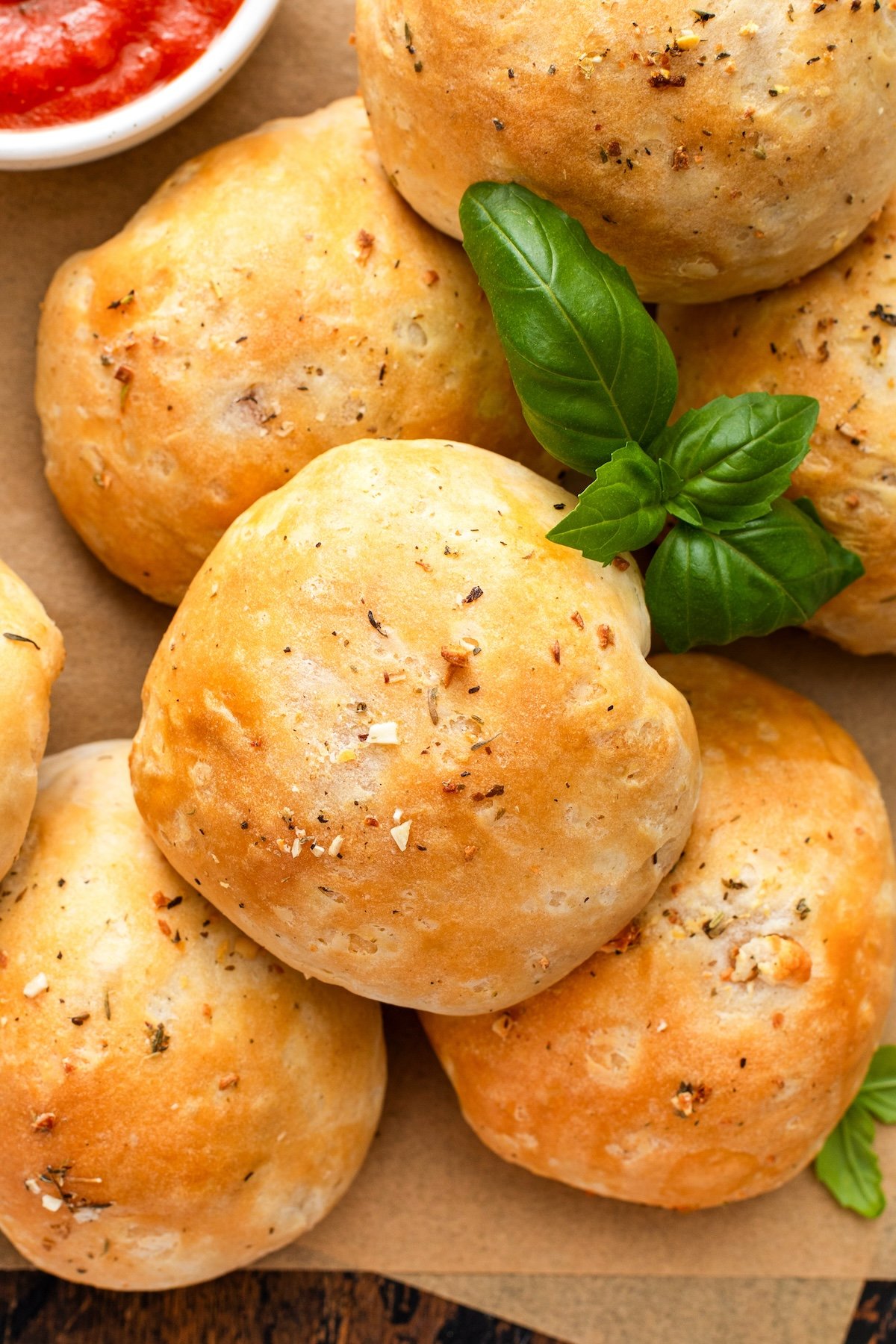 A batch of freshly baked meatballs, sauce, and cheese wrapped in biscuit dough presented with fresh herbs.