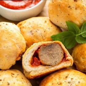 A halved meatball bomb on a serving plate with more meatball bombs.