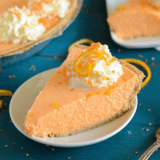 No-Bake Creamsicle Pie on a white plate topped with whipped cream and orange zest