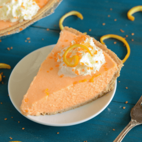 No-Bake Creamsicle Pie on a white plate topped with whipped cream and orange zest