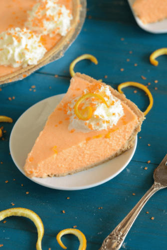 No-Bake Creamsicle Pie on a white plate topped with whipped cream and orange zest
