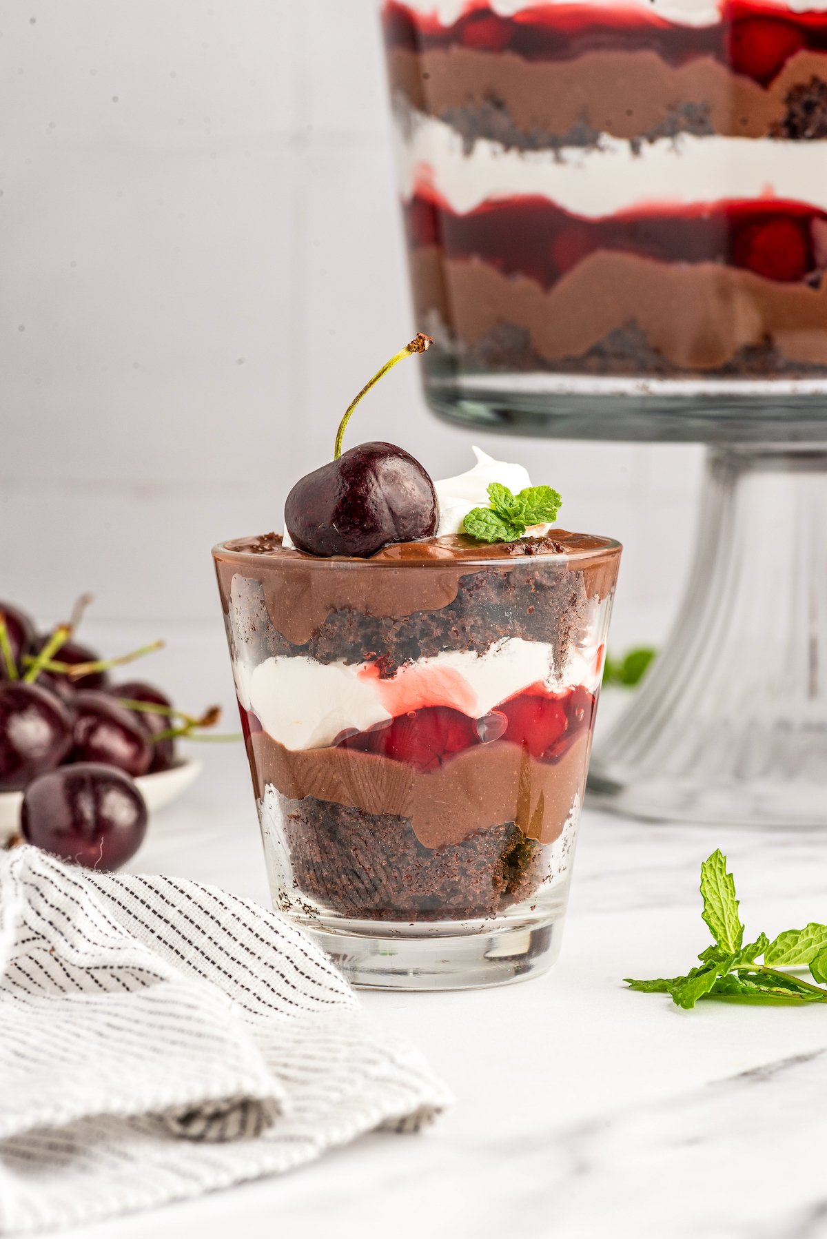 A small glass of trifle topped with fresh cherries.