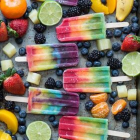Rainbow Popsicles Surrounded by Various Fruits