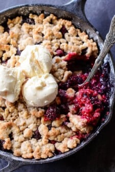 Skillet Berry Cobbler in a cast iron skillet topped with crumble and vanilla ice cream