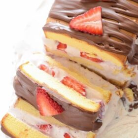 A strawberry ice cream cake cut into slices, topped with strawberries.