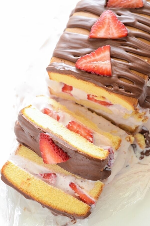 A strawberry ice cream cake cut into slices, topped with strawberries.