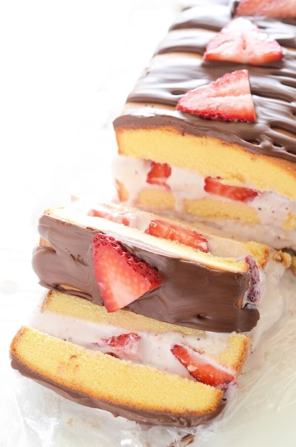 A strawberry ice cream cake cut into slices, topped with strawberries.