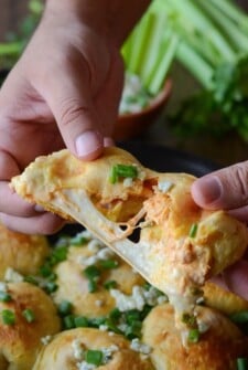 Two hands pulling apart a buffalo chicken mozzarella bomb