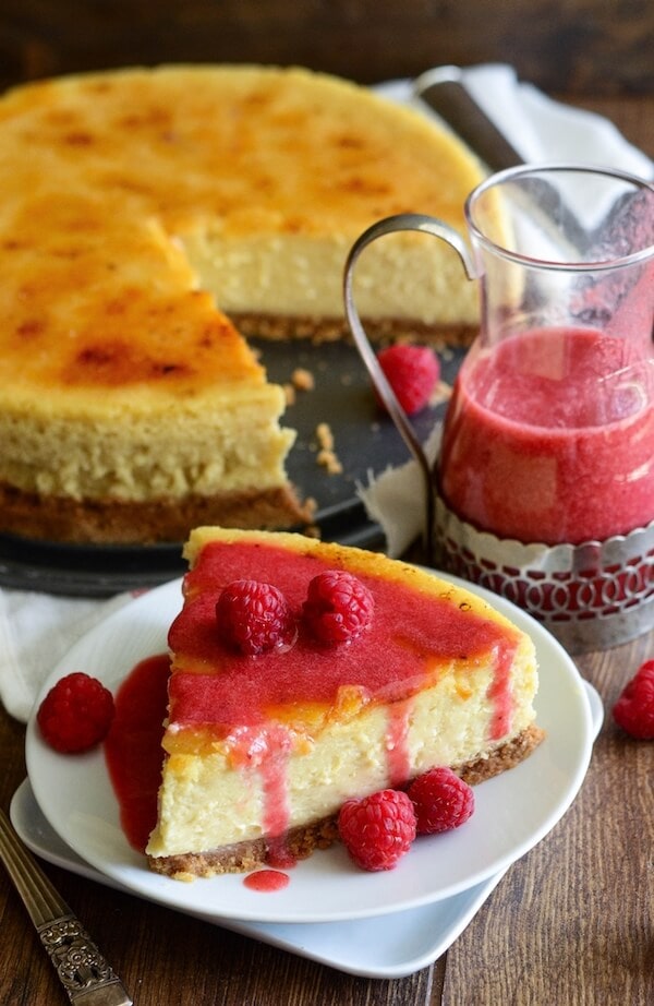 A Slice of Creme Brulee Cheesecake Beside the Remaining Cheesecake on a Wooden Table