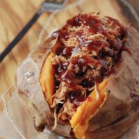 A Pulled Pork Stuffed Sweet Potato on a Piece of Parchment Paper