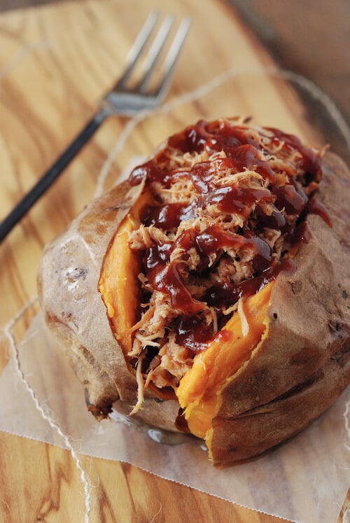 A Pulled Pork Stuffed Sweet Potato on a Piece of Parchment Paper