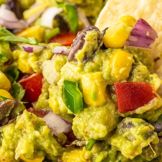Landscape photo of a corn chip being dipped into guacamole.