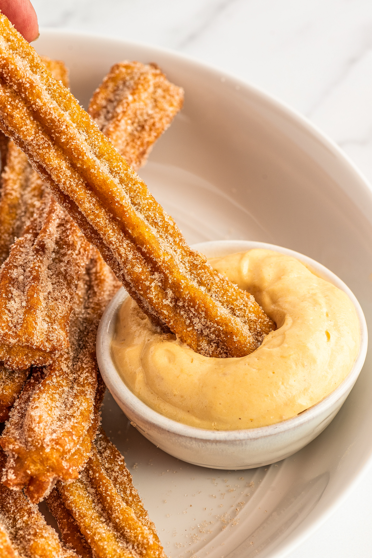 Dipping a pumpkin churro into the cinnamon pumpkin cream cheese dip.