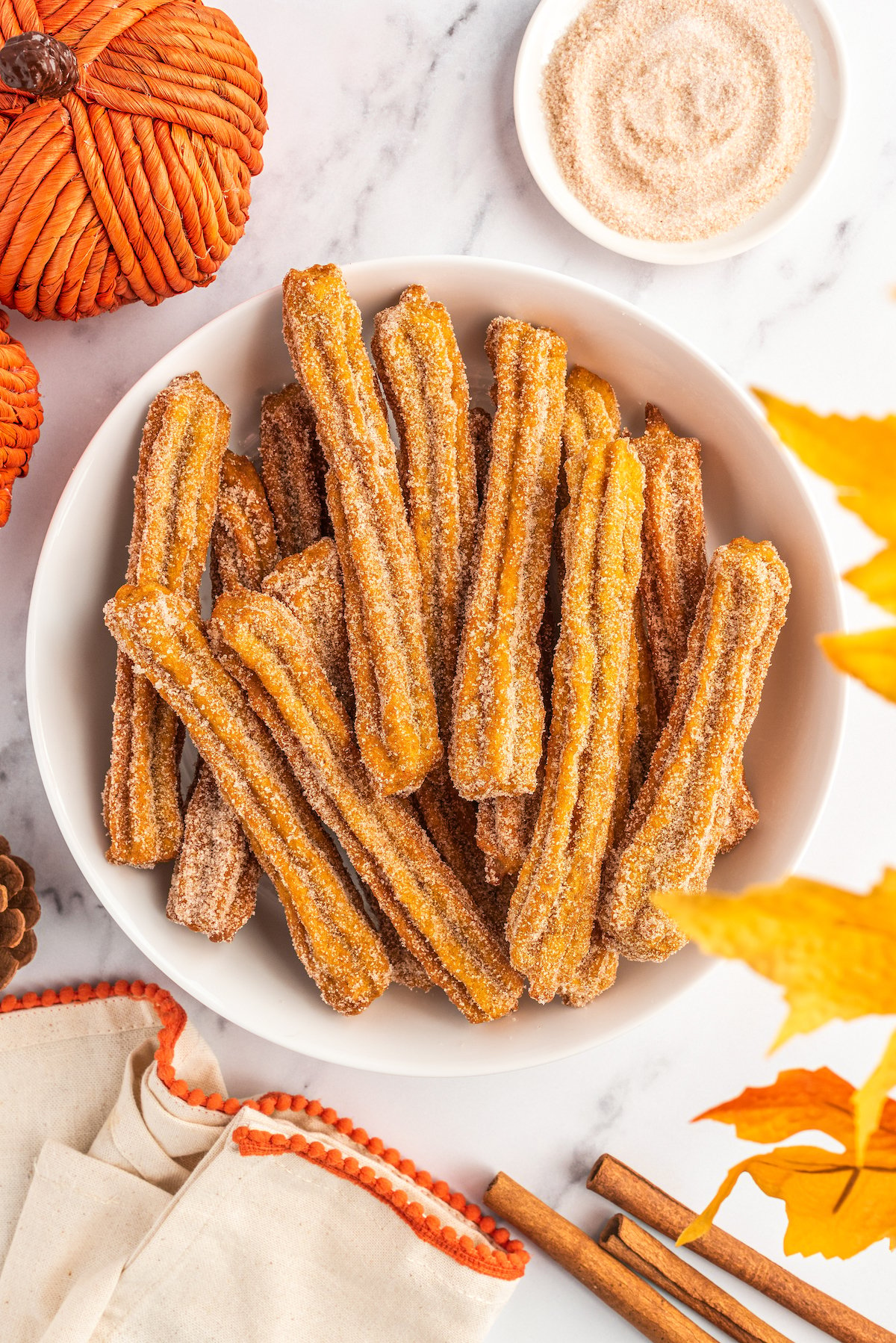 Pumpkin churros with cinnamon sugar in a bowl on the side.