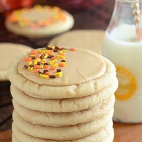 A stack of soft maple sugar cookies frosted with maple icing and topped with orange and black sprinkles.