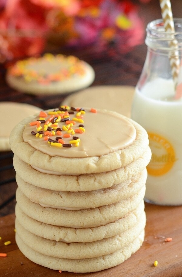 A stack of soft maple sugar cookies frosted with maple icing and topped with orange and black sprinkles.