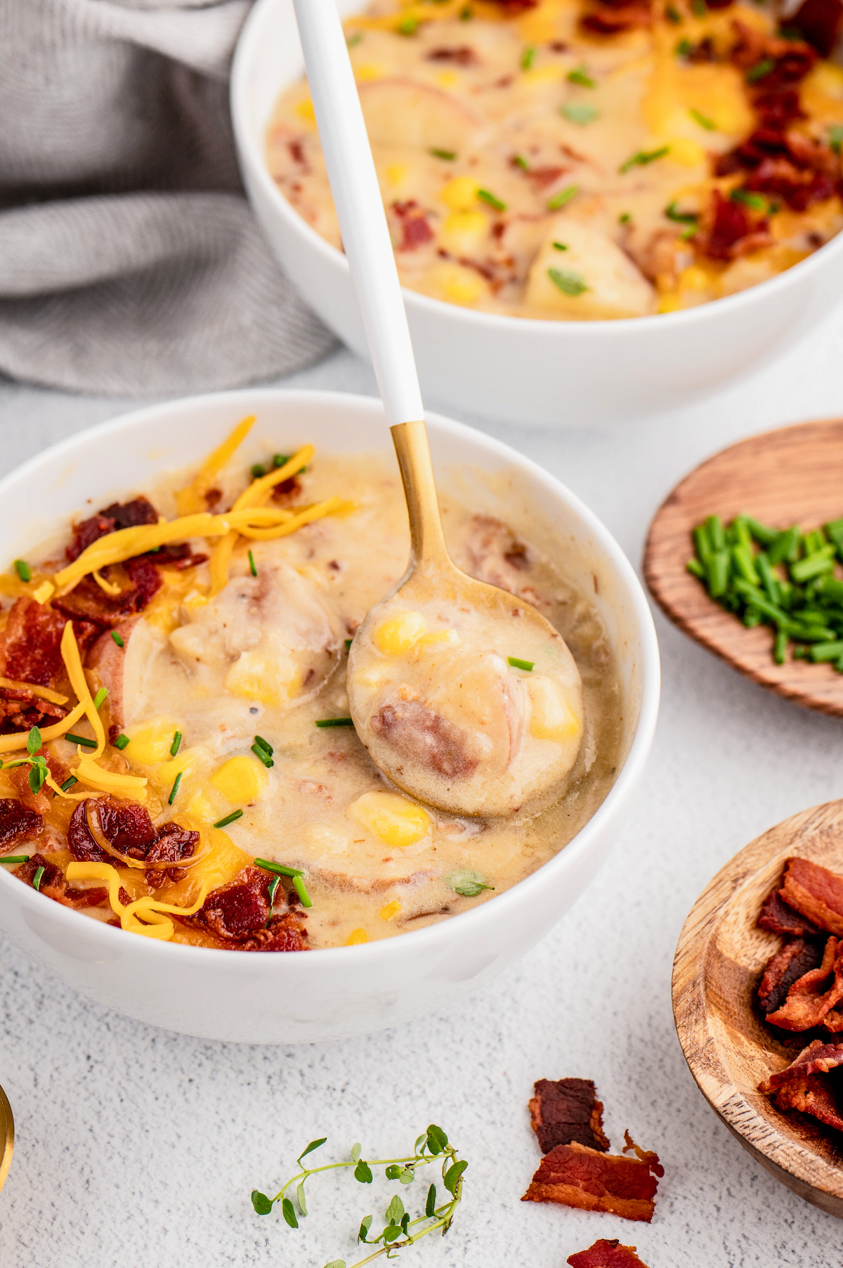 Chowder in a bowl with bacon and cheese on the side. 