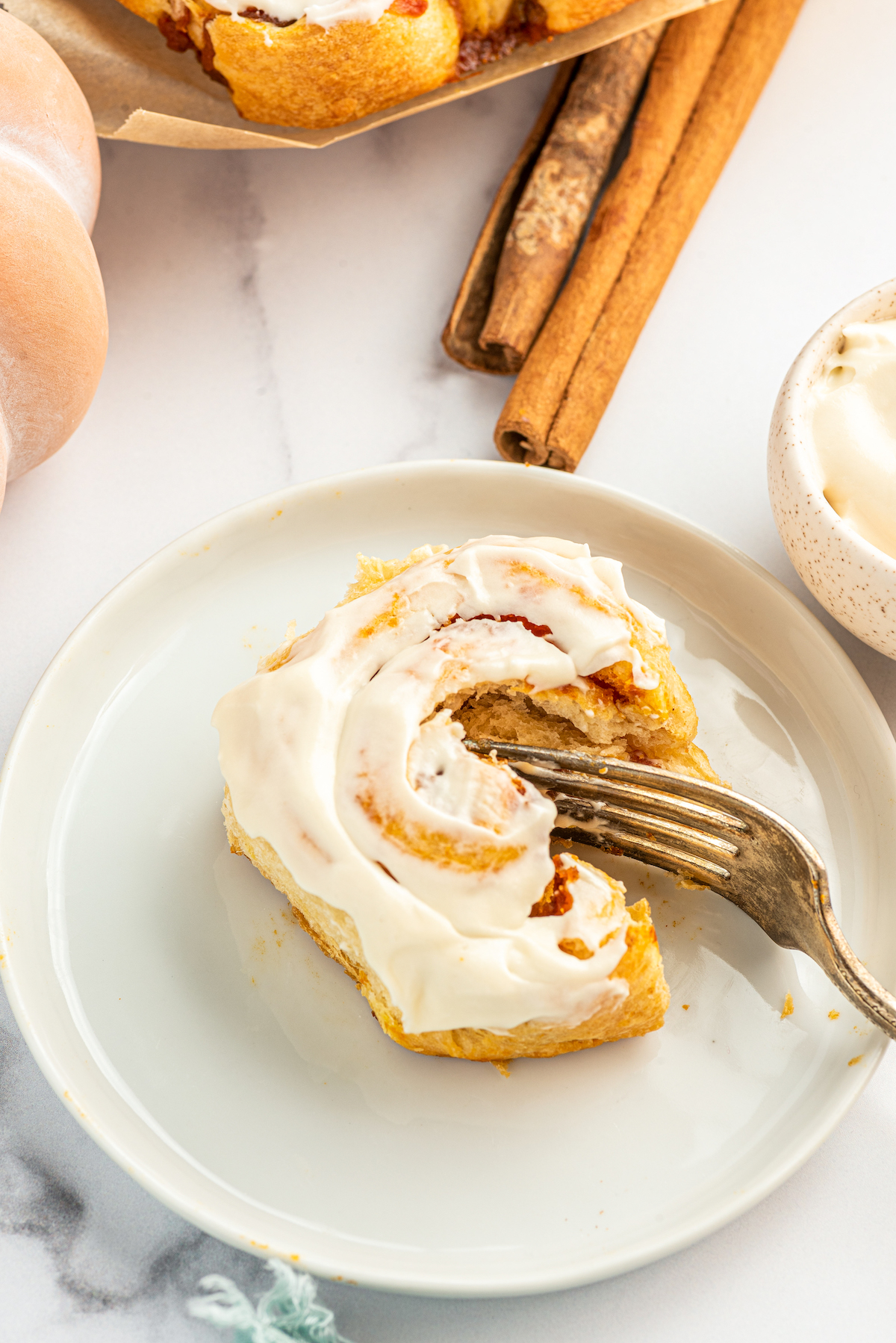 Slicing into a frosted pumpkin cinnamon roll.