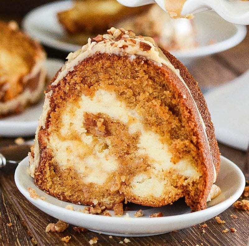 Close up of a slice of sweet potato cream cheese cake on a white plate.