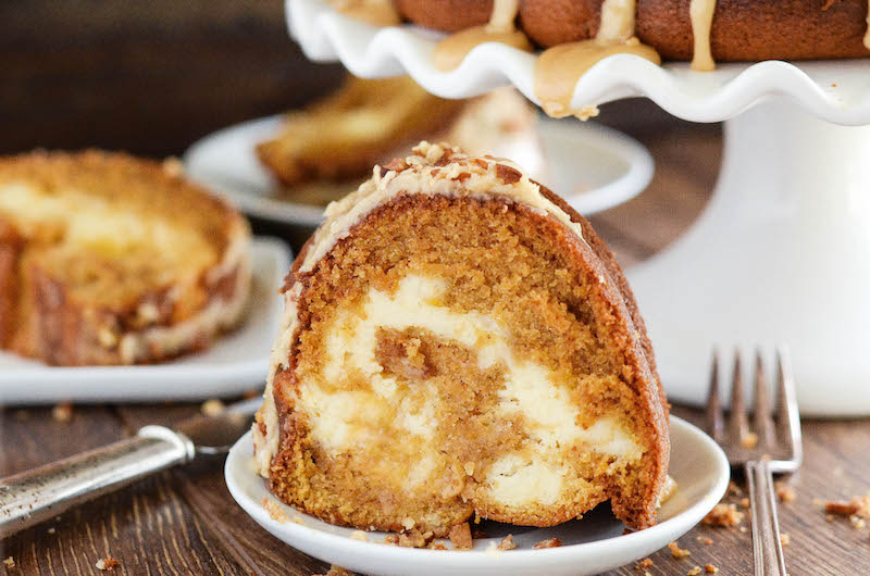 A slice of sweet potato cake with a cream cheese swirl, on a white plate.